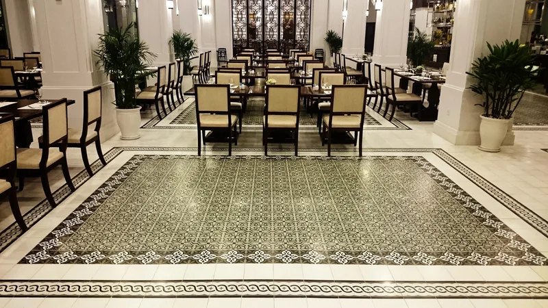 An elegant hotel restaurant in Phu Quoc features patterned tile flooring and rows of dining tables under bright chandeliers.