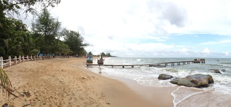A quiet sandy beach with fishing boats, wooden fences, and a small pier on Phu Quoc island.